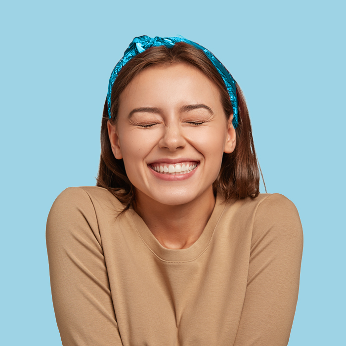 Portrait of a happy young woman with a blue bandana in front of a lite blue background